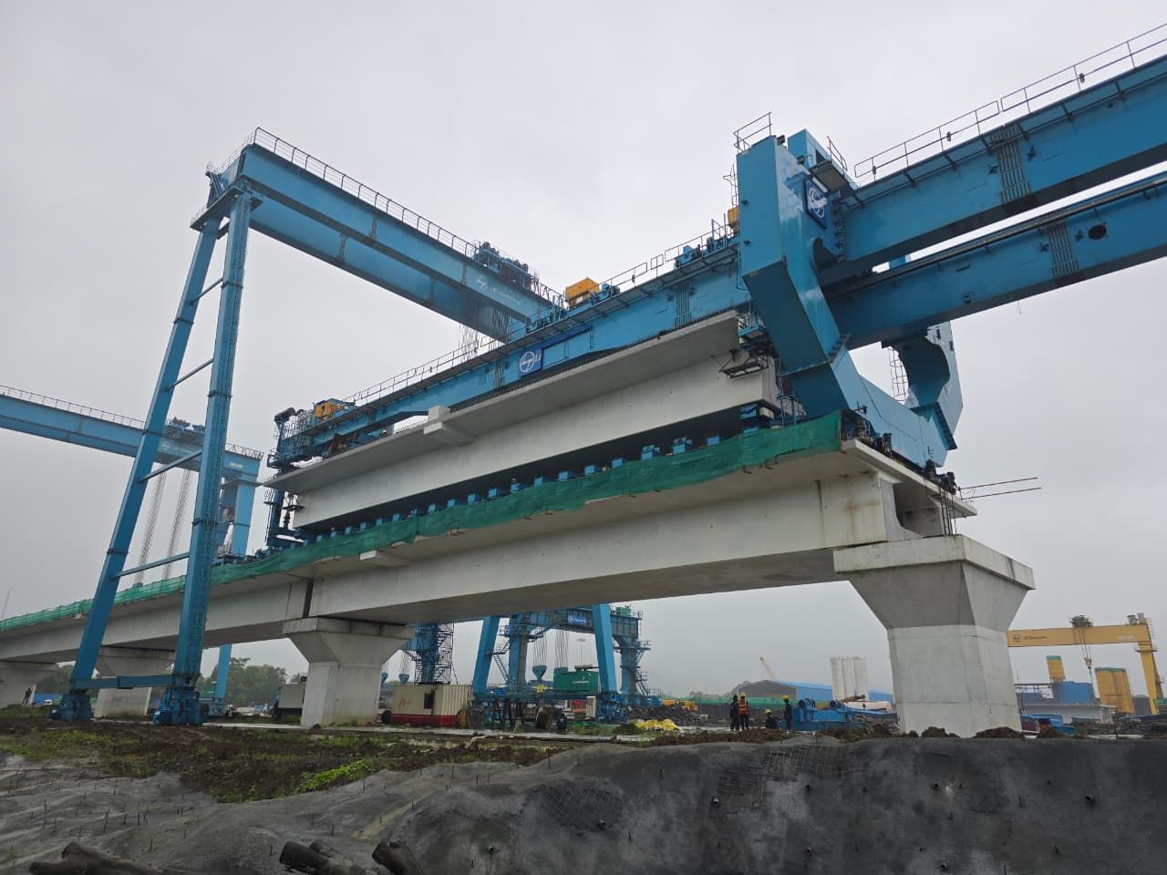 Blue straddle launcher placing precast girders on piers of an elevated high-speed rail viaduct