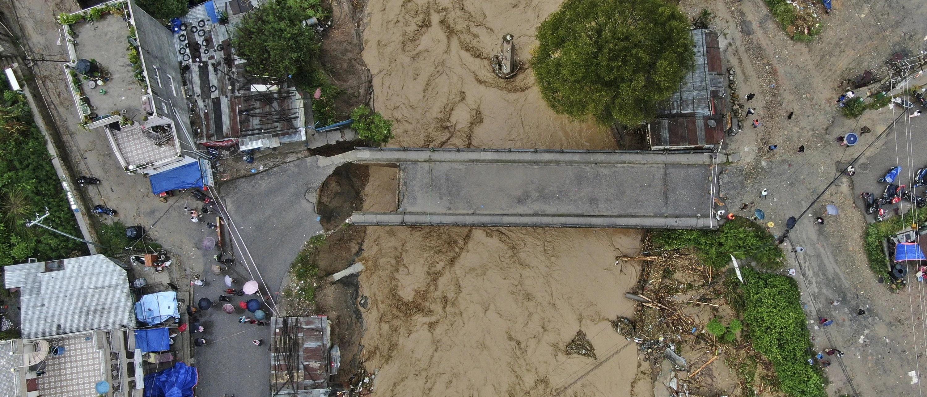 Aerial view of a road bridge severed from its approach by a swollen muddy flooded river