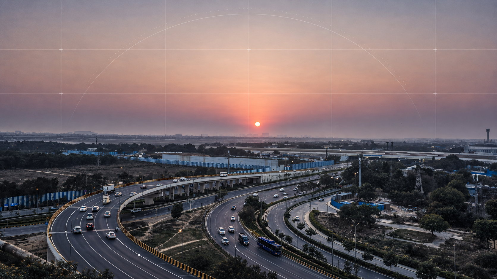 An elevated highway interchange curves through a developing urban landscape beneath a warm sunset, with infrastructure and construction activity extending toward the horizon.