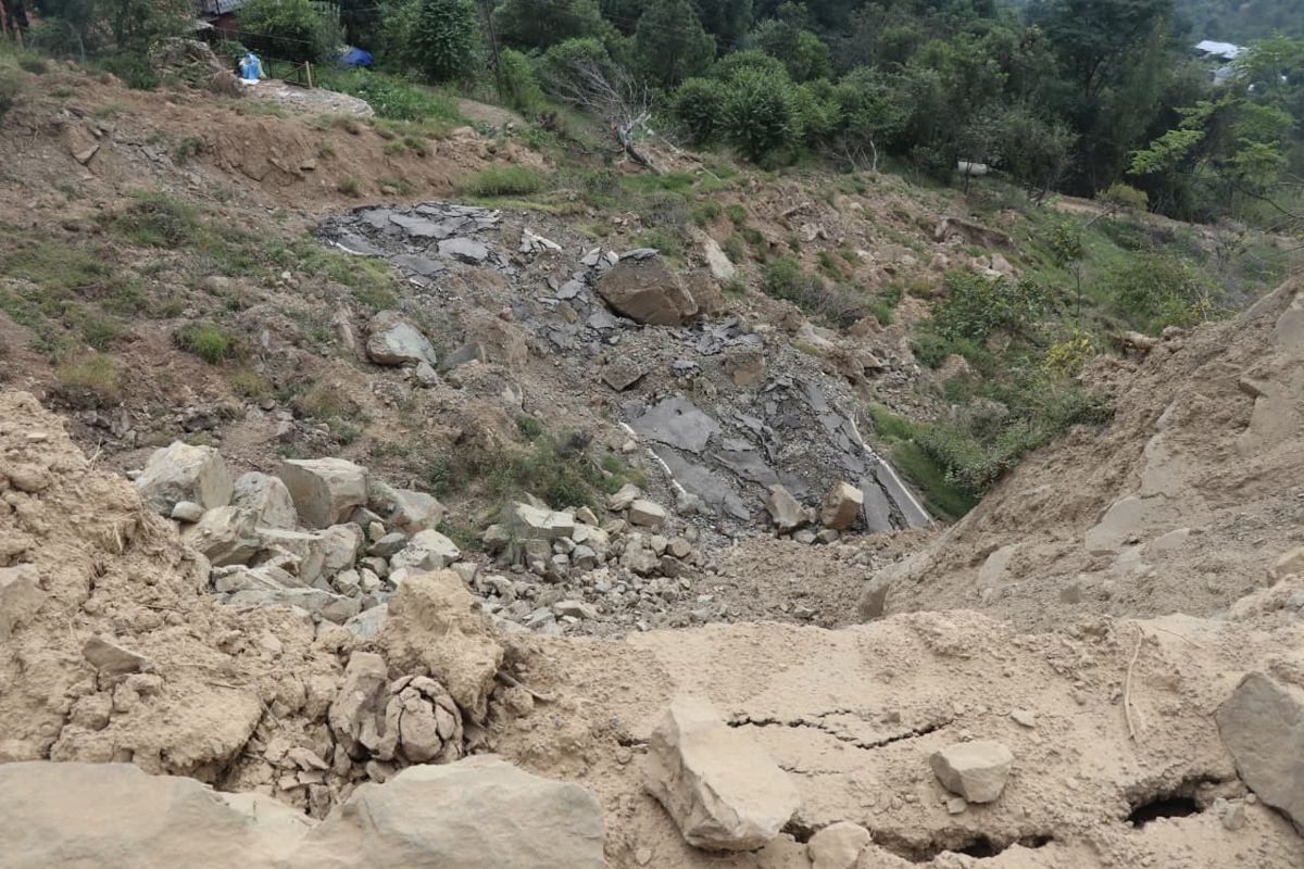 Collapsed slope and rock debris across a hill road