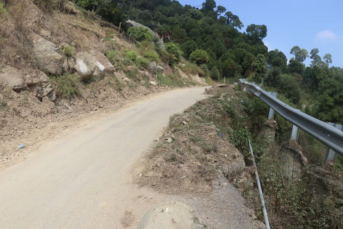 Hill road with an eroded embankment and guard rail beside it